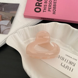 Gros plan d'une pince à cheveux rose brillant en forme de rose sur un plateau décoratif