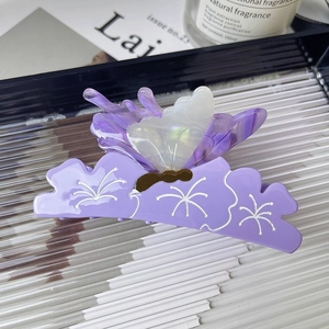 Elegant purple butterfly hair claw clip with floral patterns on a glass tray