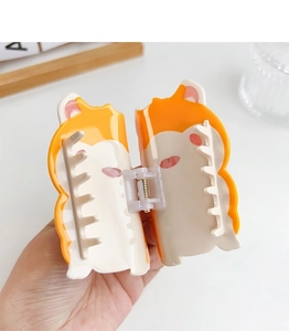 Close-up of cute orange and white Shiba Inu hair claw clip held in hand for hair styling