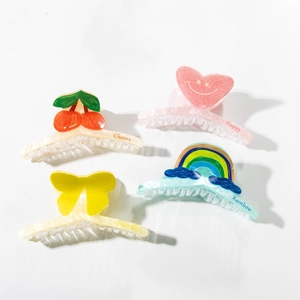 Close-up of four acrylic hair claws with cherry, rainbow, and butterfly printed patterns
