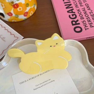Detailed top view of a bright yellow acetate cat-shaped hair claw clip on a white tray