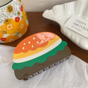 Detailed view of an acetate hamburger-shaped hair claw clip on a white paper background