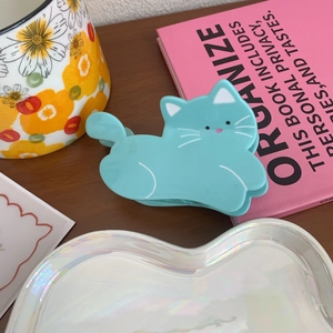 Close-up of a cute light blue acetate cat-shaped hair claw clip on a wooden table