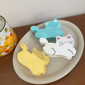 Cute acetate cat hair claws in mint green, white, and yellow on a ceramic tray