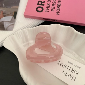 Détail de la pince à cheveux cœur en résine rose translucide sur plateau déco