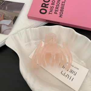 Vue détaillée d'une grande pince à cheveux rose pâle en résine dans un bol en céramique