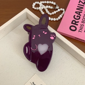 Macro detail of dark purple bunny hair claw with pink heart and glossy finish