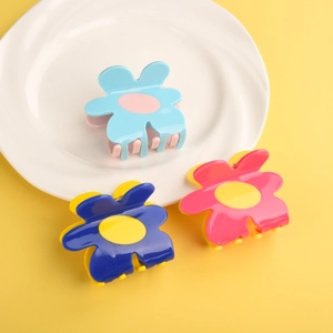 Detail showing colorful flower-shaped hair claws in blue and pink on a white plate