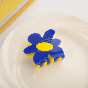 Detailed macro view of the blue flower hair claw clip with vibrant yellow center core