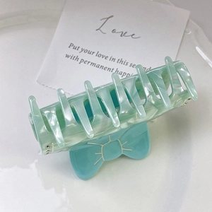 Vue détaillée de la texture marbre vert menthe et du nœud bleu sur la pince à cheveux