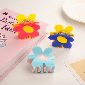 Three elegant acetate flower hair claws in vibrant pink, blue, and yellow floral designs
