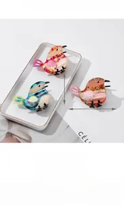 Detailed macro view of bird-shaped acetate hair claws with marble texture in three colors