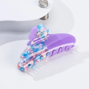 Dettaglio del fermaglio per capelli in acetato viola con motivo floreale e strass