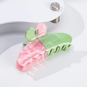 Dettaglio molletta per capelli in acetato rosa e verde con fiori e strass lucidi
