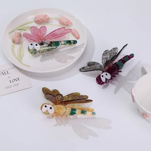 Detailed view of 3D dragonfly hair clips in marble, zebra, and leopard acetate finishes