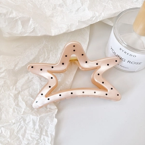 Macro detail of peach pink star hair claw clip with black polka dots and gold spring