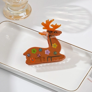Close-up of reindeer shaped acetic acid hair claw with colorful rhinestones on white tray