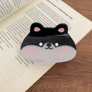 Close-up of a glossy acetate dog-shaped hair claw clip on a book background