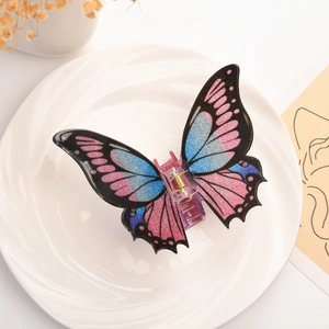 Macro detail of 3D butterfly hair claw with pink blue gradient and glitter finish