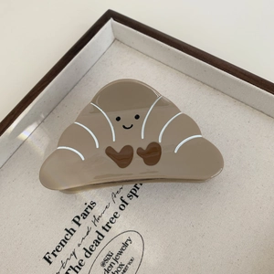 Detail view of croissant shaped brown acetate hair claw clip with cute heart on a tray
