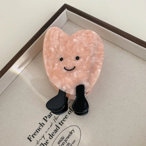 Detail of pink marble acetate heart hair claw clip with cute cartoon face design