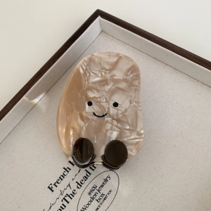 Macro detail of smiley face acetate hair claw clip with cream marble texture finish