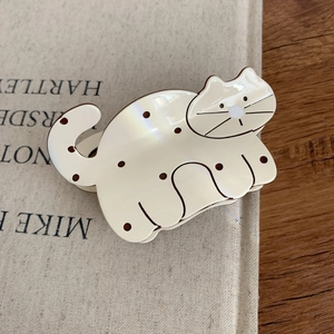Close-up of cute cream cat hair claw clip with brown dots on a rustic wooden table
