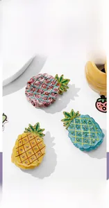 Détail de pinces à cheveux ananas avec strass en couleurs rose, bleu et jaune