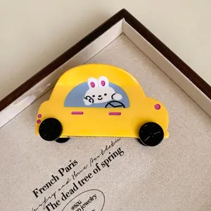 Détail macro d'une pince à cheveux jaune en acétate en forme de voiture de dessin animé