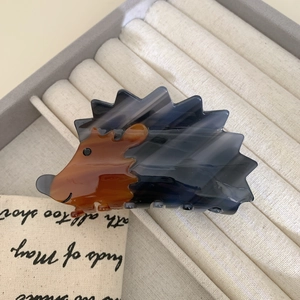 Detailed close-up of a cute hedgehog-shaped acetate hair claw clip with marbled textures