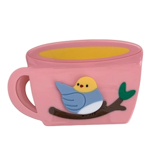 Rosafarbene Kaffeetasse Haarklammer mit süßem blauen Vogel und grünem Blatt auf Weiß