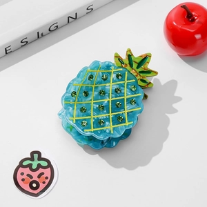 Détail de la pince à cheveux ananas bleue translucide avec strass verts et grille jaune