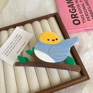 Detail of bird-shaped acetate hair claw clip with colorful design on velvet display