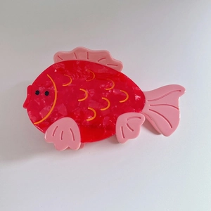 Detail view of puffer fish hair claw clip made of red marble texture acetate material