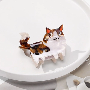 Detail einer Calico-Katzen-Haarklammer aus Acetat auf einem Tablett mit Kaffee