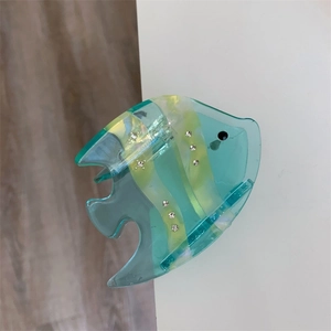 Detail of fish-shaped mint green acetate hair claw with yellow stripes and rhinestones