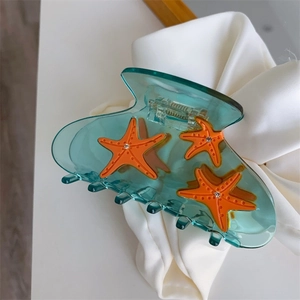 Detail showing translucent green hair claw with orange starfish and sparkly rhinestones