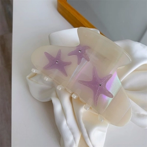 Creamy ocean starfish hair claw clip with purple rhinestones on white silk background