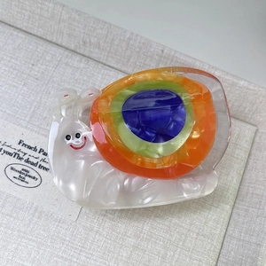 Detail view of a snail-shaped cellulose acetate hair claw with rainbow gradient shell