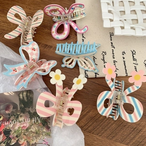 Set of pastel floral and bow hair claw clips for women on a rustic tabletop decor