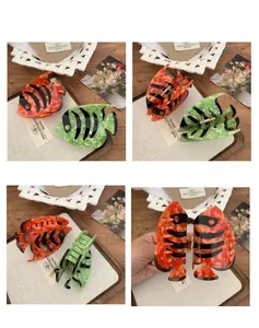 Detailed close-up of fish-shaped cellulose acetate hair claws with marble textures