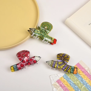 Three creative pencil-shaped hair claws in green, pink, and purple acetate resin