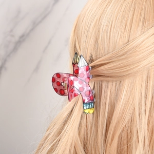 Pink pencil-shaped hair claw clip with red polka dots on a woman with blonde hair