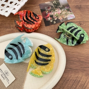 Colorful acetate tropical fish hair clips with marble texture on a wooden desk background