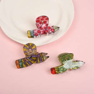 Detail shot of colorful pencil-shaped hair claws in creative patterns on a white plate