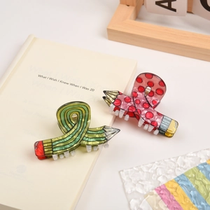 Macro detail of pencil shaped hair claw clips in pink polka dot and green stripe designs