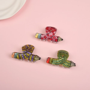 Three creative pencil-shaped hair claws in red polka dot and colorful striped patterns