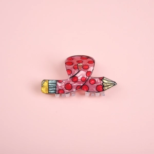 Close-up of a pink pencil shaped hair claw clip made of acetate with red polka dots detail