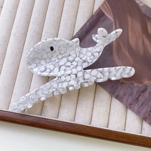 Détail de la pince à cheveux baleine en acétate avec texture marbrée blanche en boîte