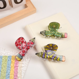 Creative pencil shaped hair claws in red, green, and purple on a notebook background